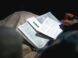 person holding black pen and writing on white notebook