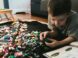 boy in grey crew-neck t-shirt plays LEGO bricks with white manual book