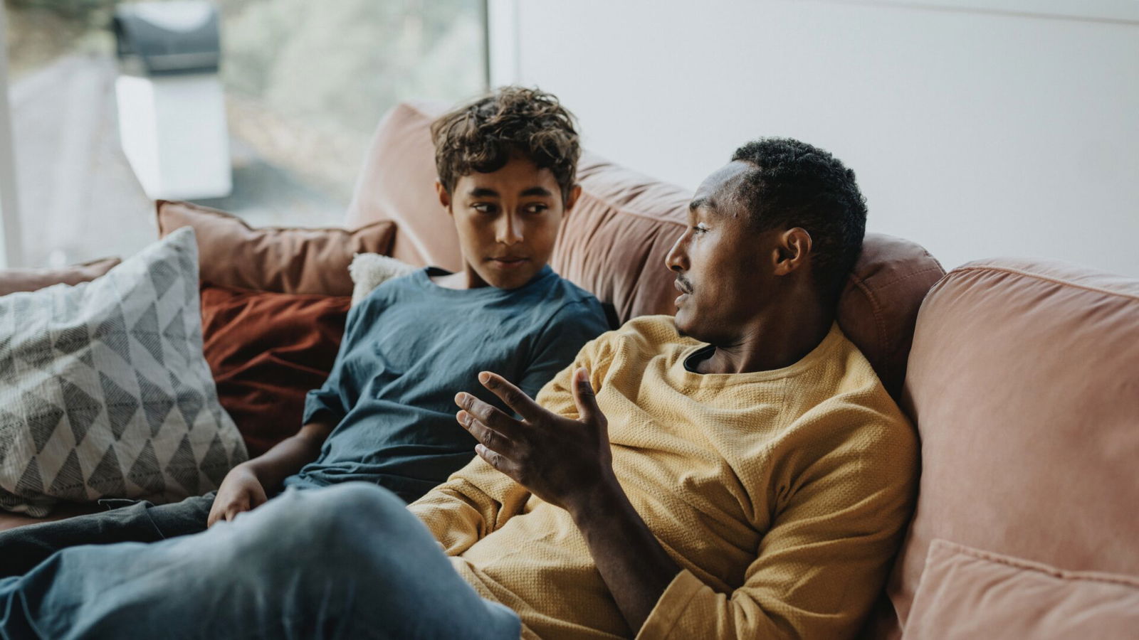 Father talking with son while sitting on sofa in living room at home - stock photo Father talking with son while sitting on sofa in living room at home - stock photo