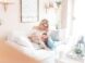 woman and baby sitting on white sofa