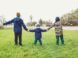 three children holding hands standing on grasses
