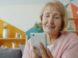 Elderly woman smiling while looking at smartphone.