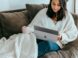 a woman sitting on a couch holding a laptop