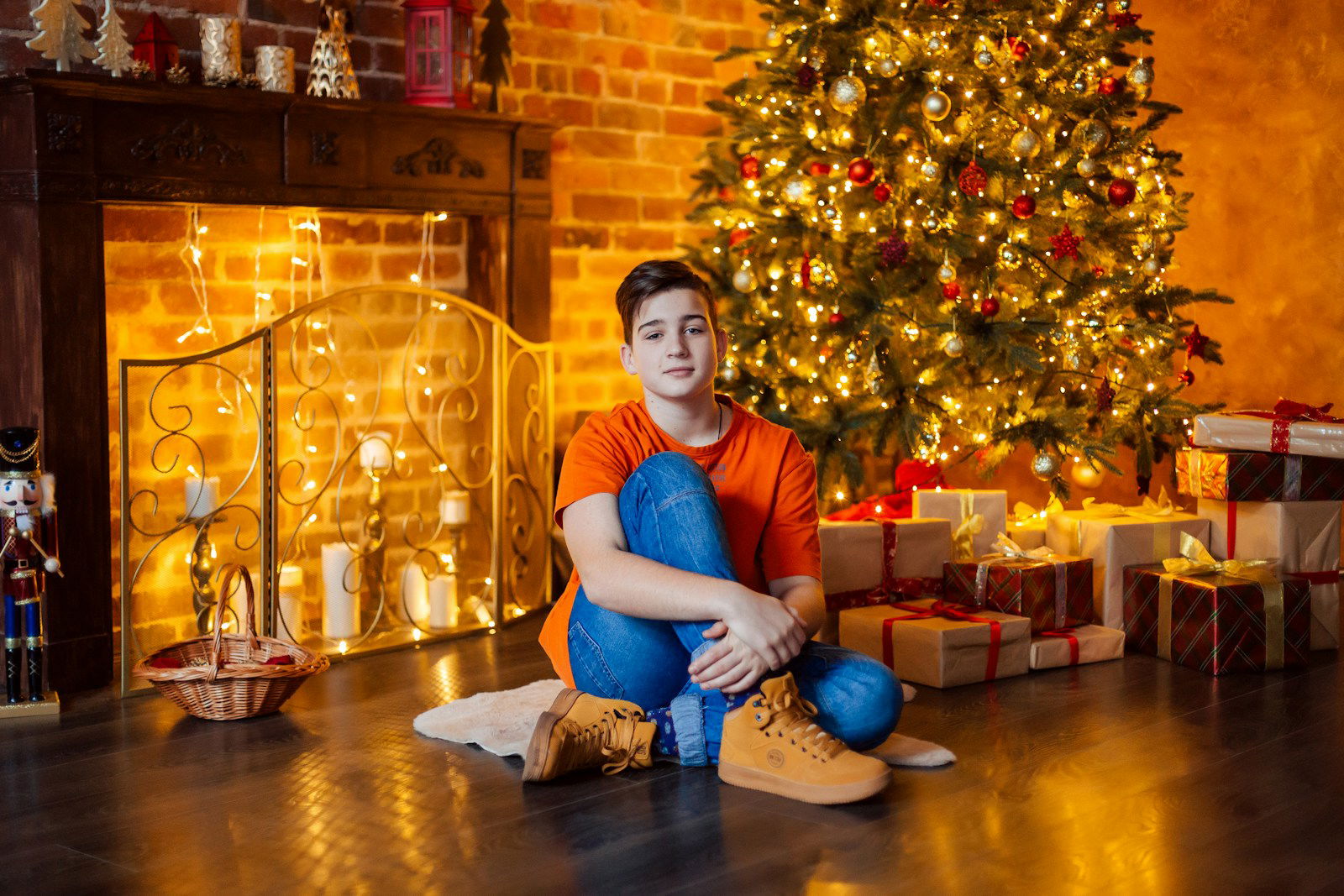 a boy sitting on the floor in front of a christmas tree