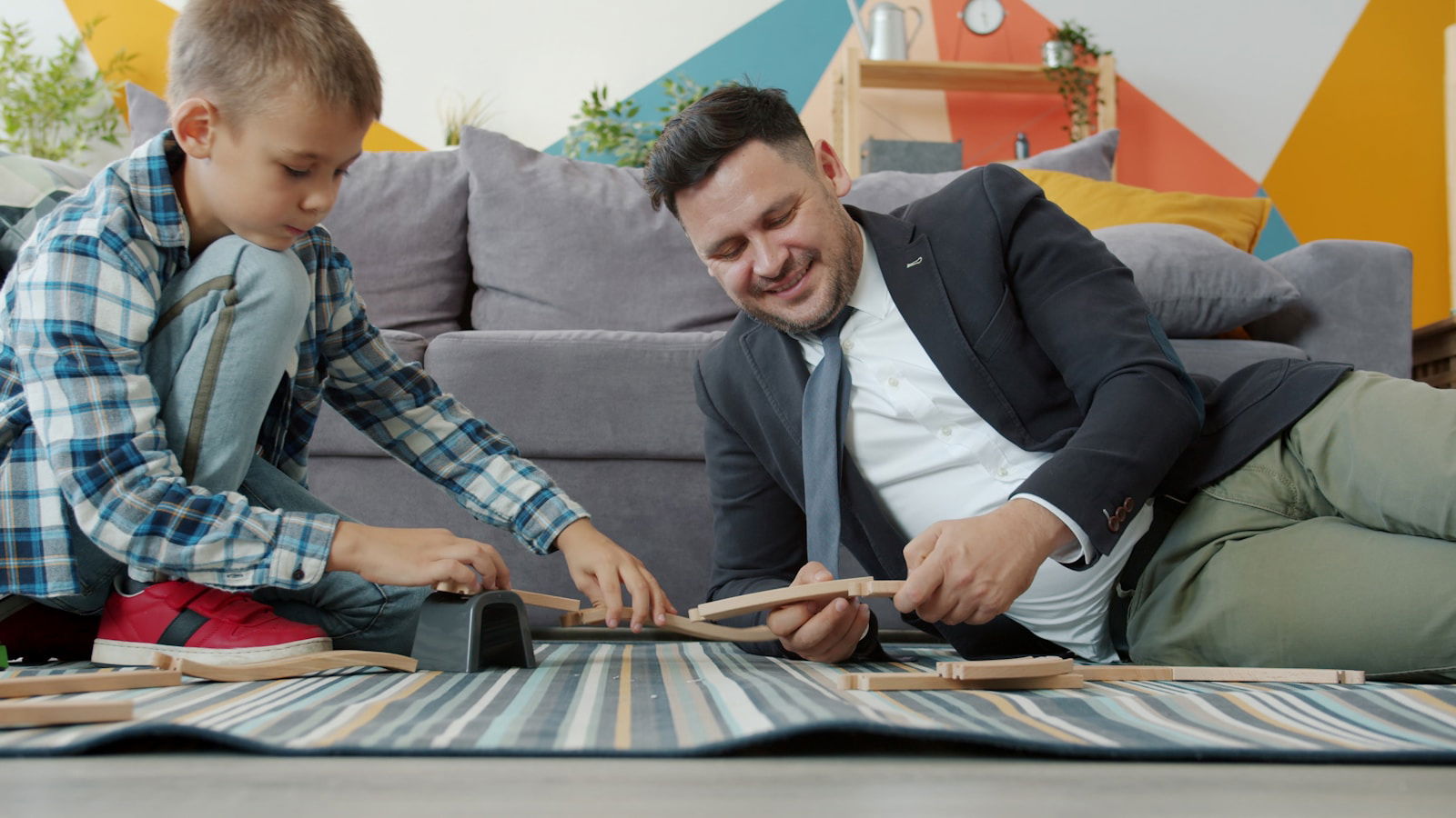 Father and son playing with a toy train set.