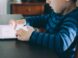 boy sitting on chair beside table using tablet computer