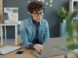 Woman with curly hair working on laptop at desk.
