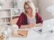woman smiling holding glass mug sitting beside table with MacBook