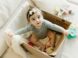 A little girl sitting inside of a box on a bed