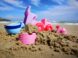 a pink sand castle with a pink toy car and a blue toy boat