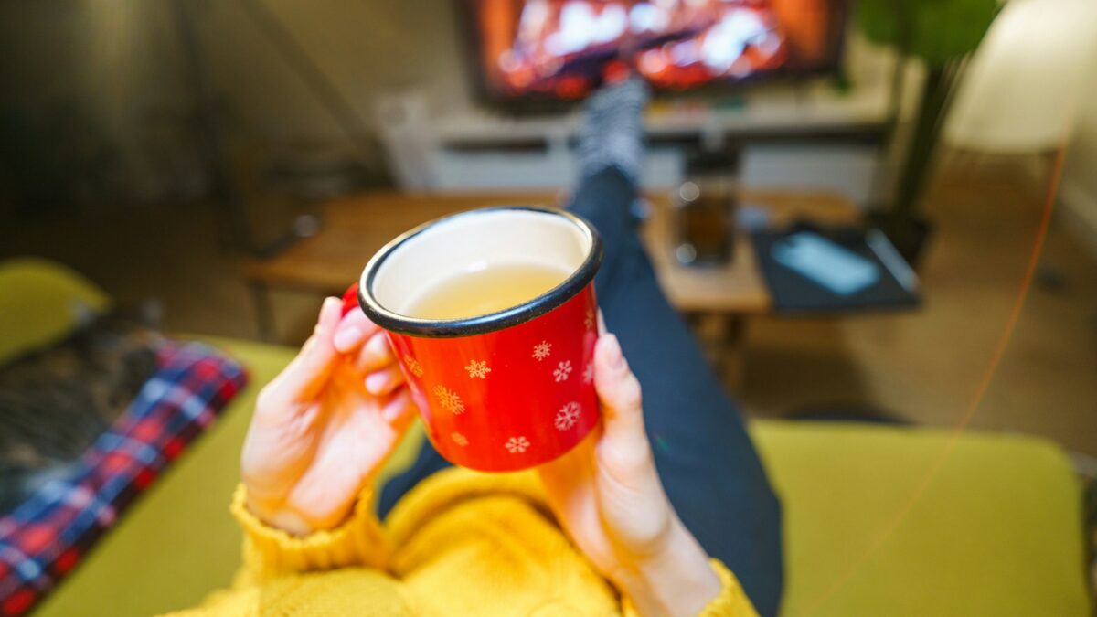 A woman holding a cup of coffee in front of a TV
