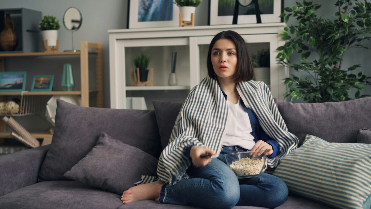 a woman sitting on a couch eating popcorn